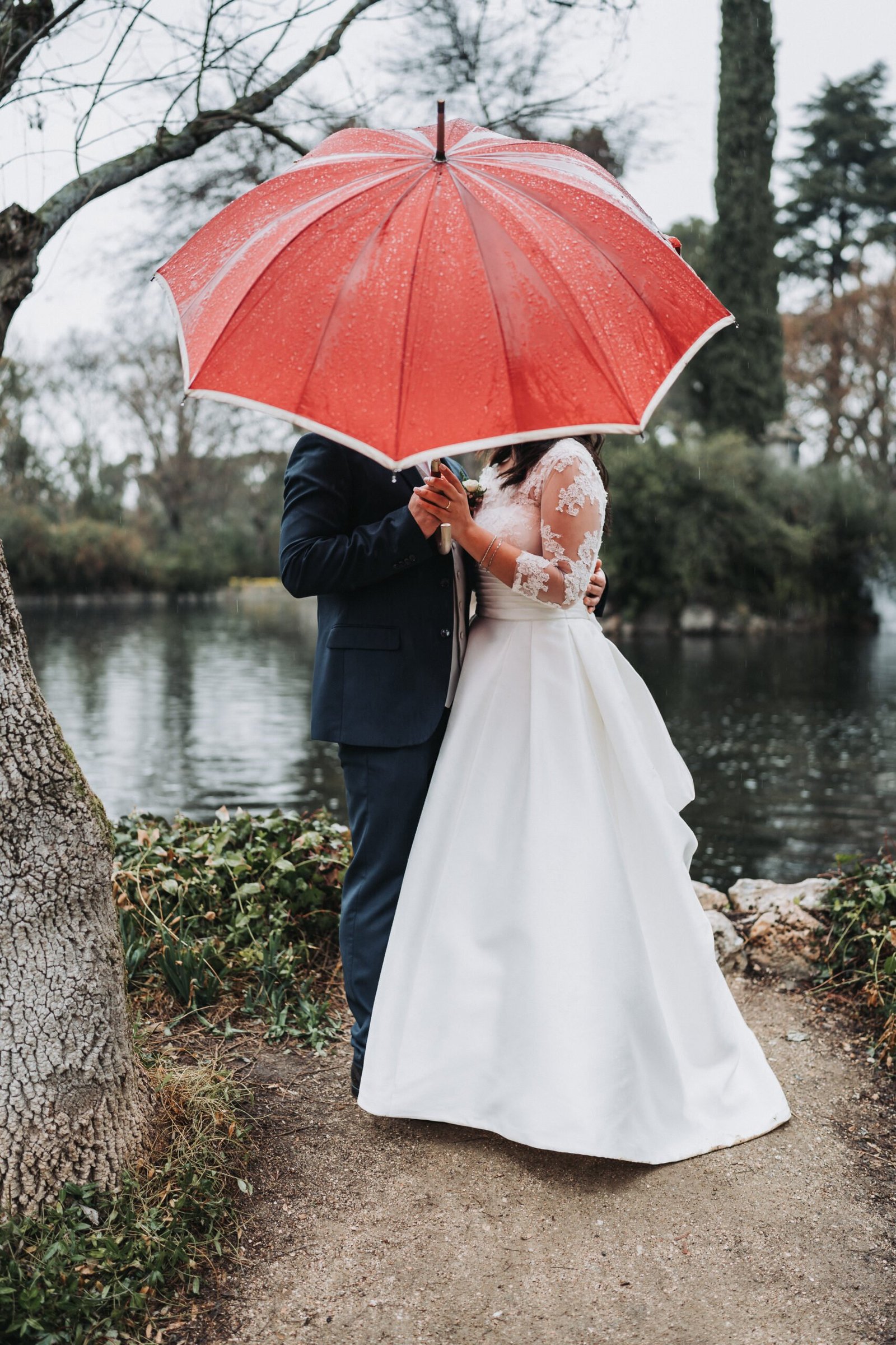 Novios bajo un paraguas durante sesión de pareja en los Jardines de El Capricho en Madrid